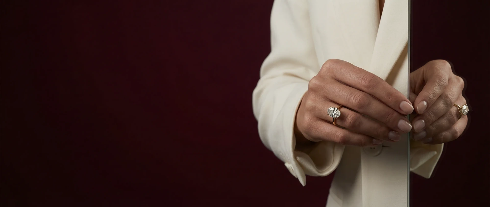 Anillo de compromiso ovalado LILY DIA con chaqueta crema junto a un espejo